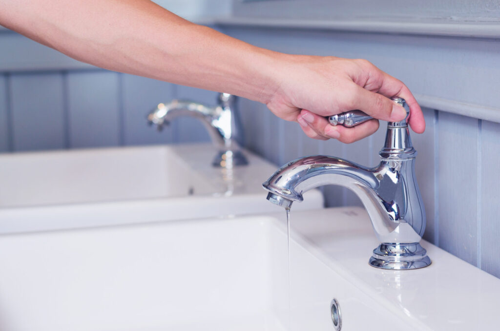 hand man opening silver faucet or water tap with white washing s hand man opening silver faucet or water tap with white washing s