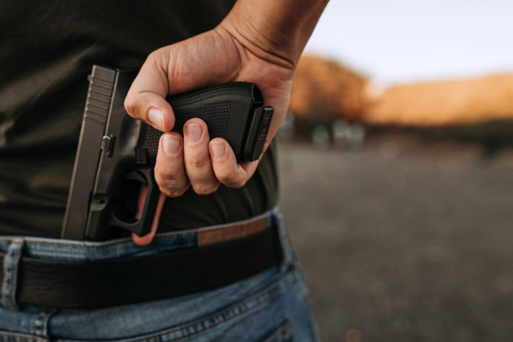 Man holding hidden short gun in his hand. tres-pessoas-baleadas-pinhais