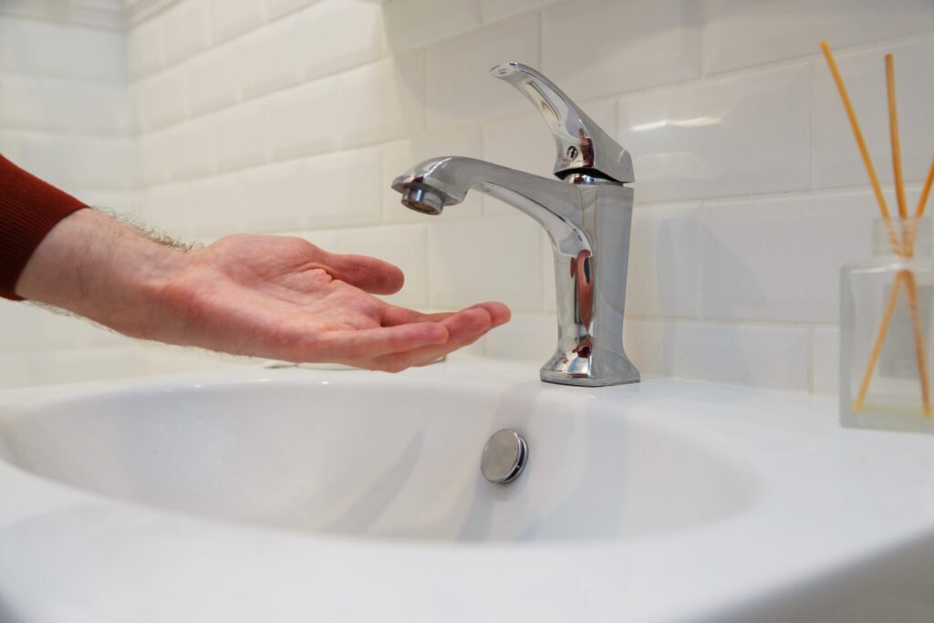 Man holding his hand under opened tap without water. Shutdown of water supply for non-payment or during repair work of the central system.