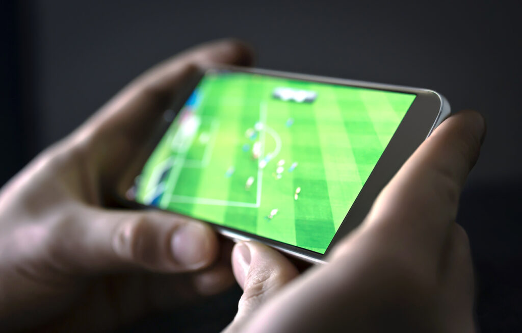 Watching football and sport stream with mobile phone. Man streaming soccer game live, video replay or highlights online with smart device.