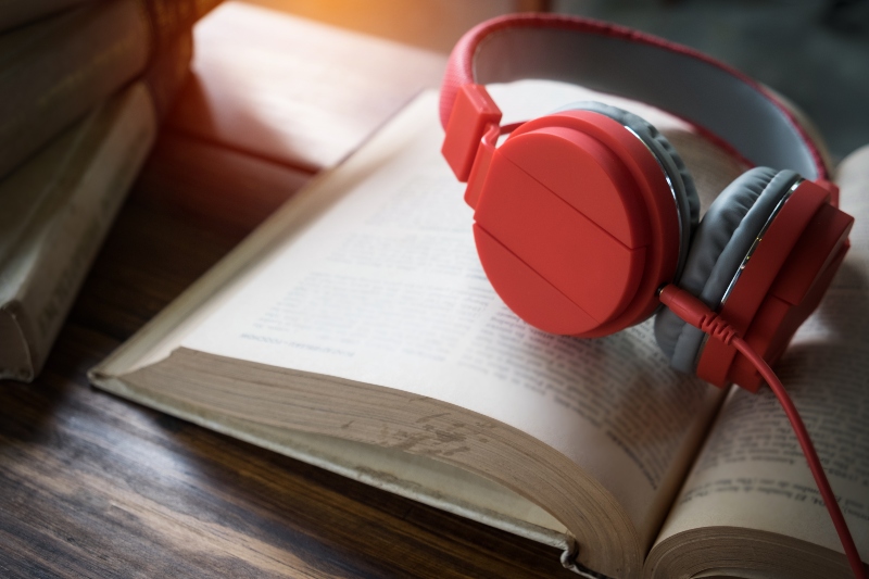 Concept of audiobook. Books on the table with headphones put on them. audiobook-diogo-e-o-surfista-topetudo
