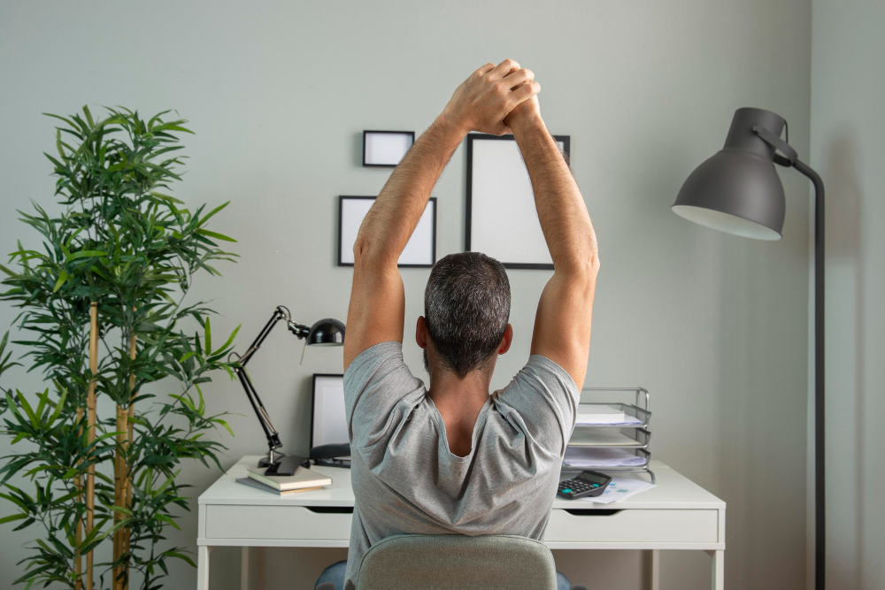 back-view-of-man-at-desk-stretching-while-working-from-home back-view-of-man-at-desk-stretching-while-working-from-home