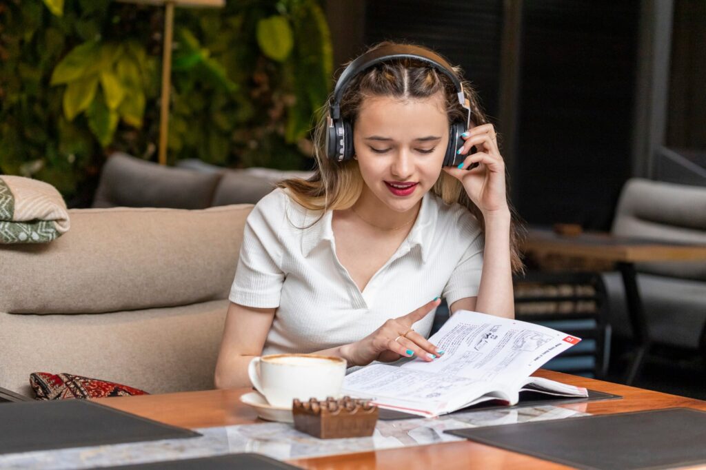 Beautiful lady listening music and reading her book at the restaurant