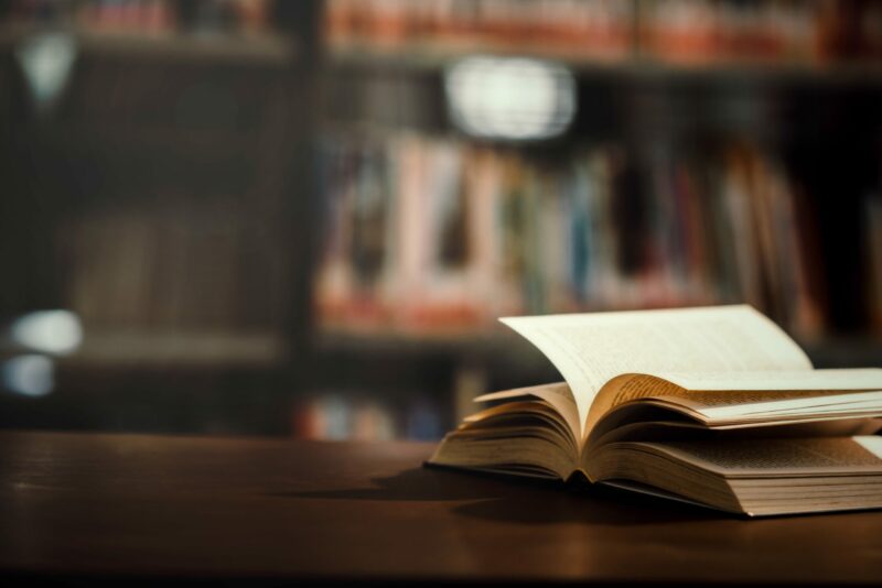 book-in-library-with-open-textbook-min-scaled-e1645204459474