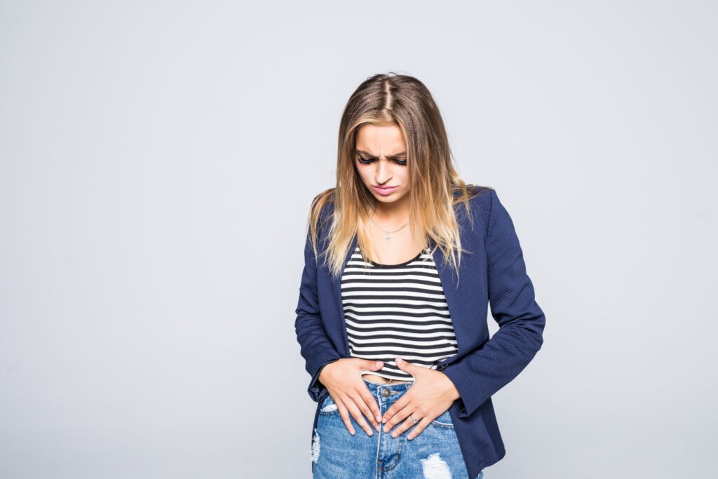 Portrait of depressed young woman with abdominal pain, looking at camera, isolated over gray background Portrait of depressed young woman with abdominal pain, looking at camera, isolated over gray background