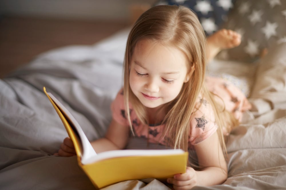 close-up-portrait-of-little-girl-reading-in-bed close-up-portrait-of-little-girl-reading-in-bed