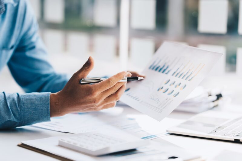 Asian Businessman working to analyze technical price graph and indicator with business team talking by cell phone. account or saving money or insurance concept.