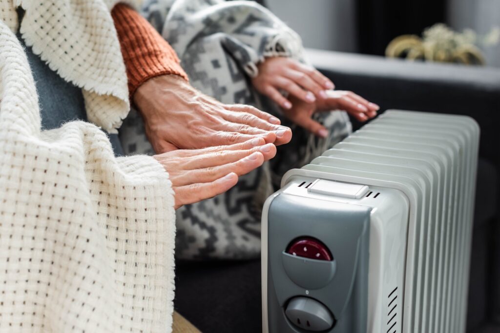 cropped view of girlfriend and boyfriend covered with blankest warming up near heater