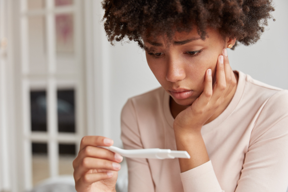 displeased-frustrated-african-american-woman-looks-stressfully-at-pregnancy-test