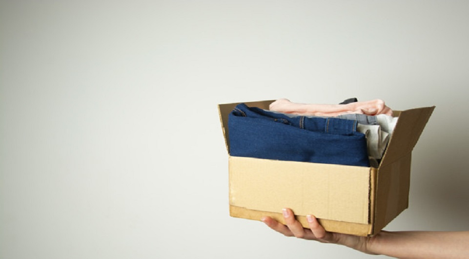 Donation concept. Hands holding donate box with clothes. Copy space.