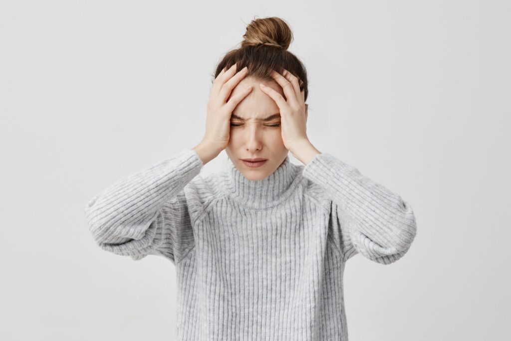 Exhausted young woman touching her head with eyes closed. Female exchange worker suffering from unbearable headache. Health concept Exhausted young woman touching her head with eyes closed. Female exchange worker suffering from unbearable headache. Health concept