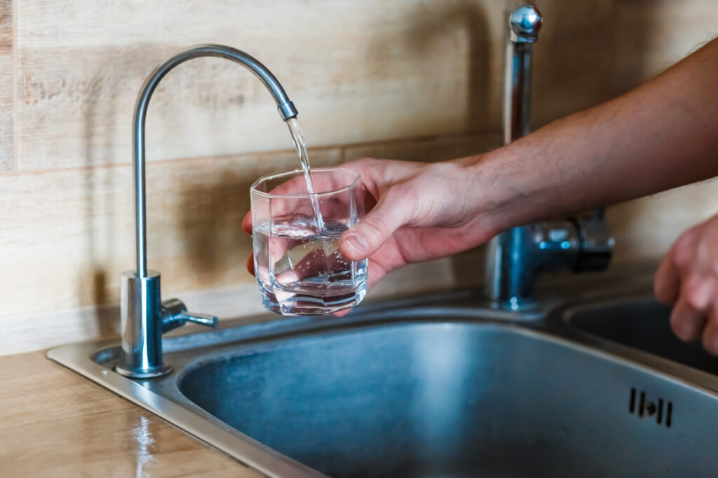 hand holding a glass of water. a man pouring water from filter falta-agua-curitiba