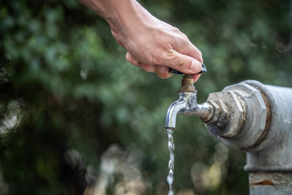 A man tries to open a tap water. A man tries to open a tap water.