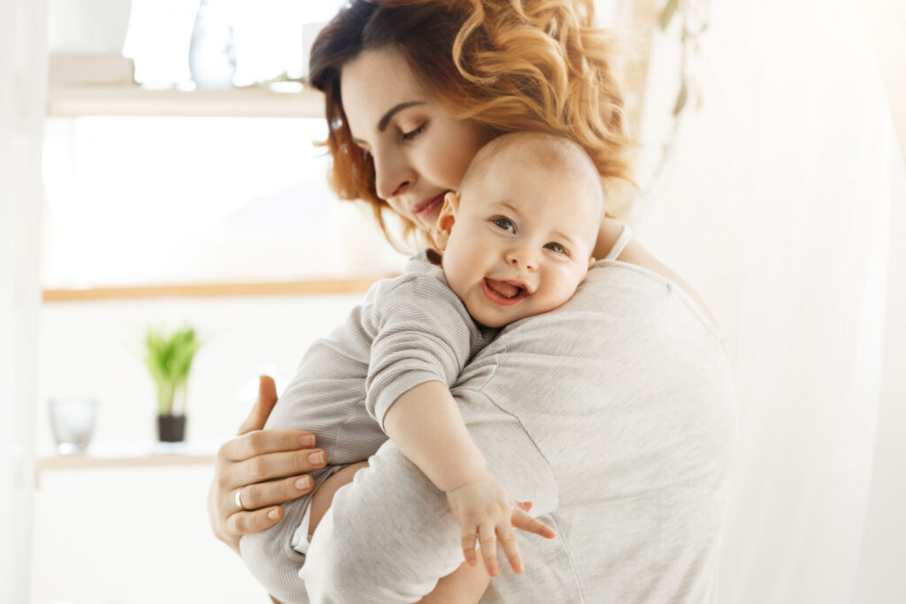 happy-young-mom-holds-precious-little-child-and-gently-hugging-his-little-body-kid-laughing-joyfully-and-looking-at-camera-with-big-grey-eyes
