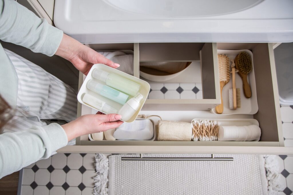 Housewife hands putting rolled up towel into drawer under sink.