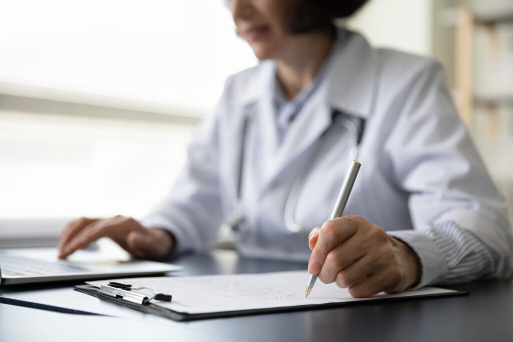 Hands of mature doctor woman filling paper medical records Hands of mature doctor woman filling paper medical records