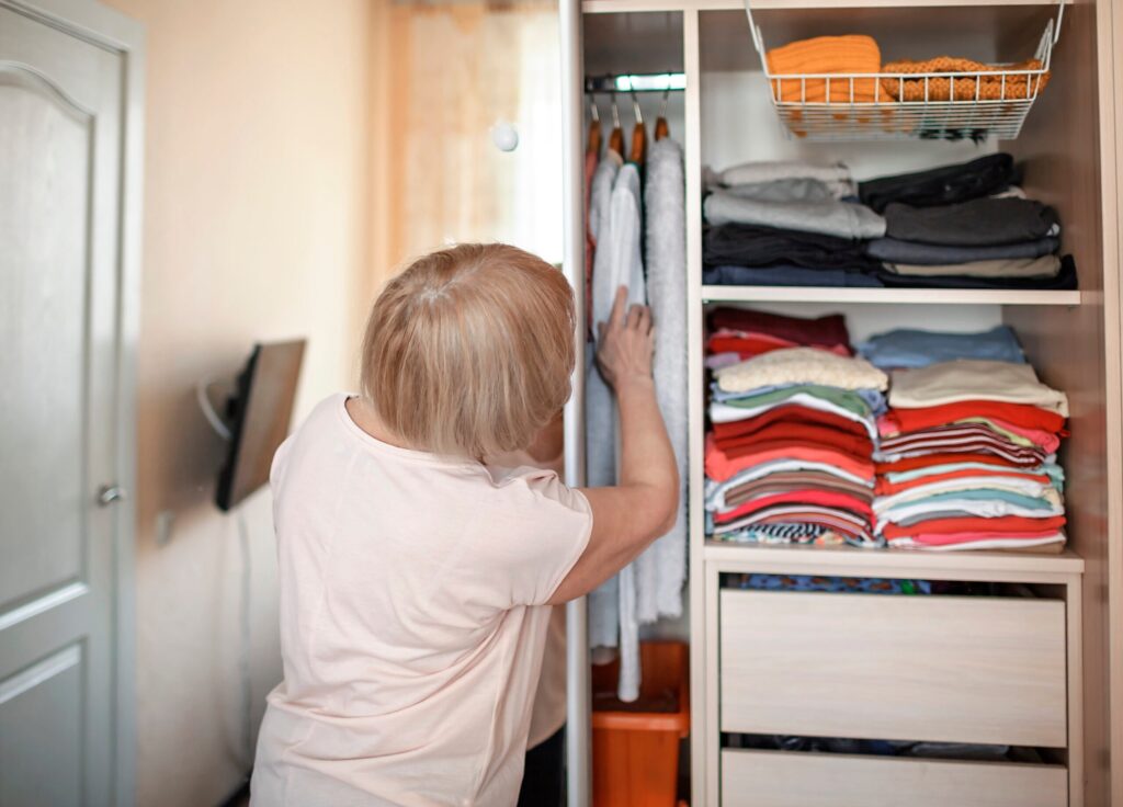 Senior woman choosing outfit from wardrobe. Cleaning, organizing and order in the closet Senior woman choosing outfit from wardrobe. Cleaning, organizing and order in the closet