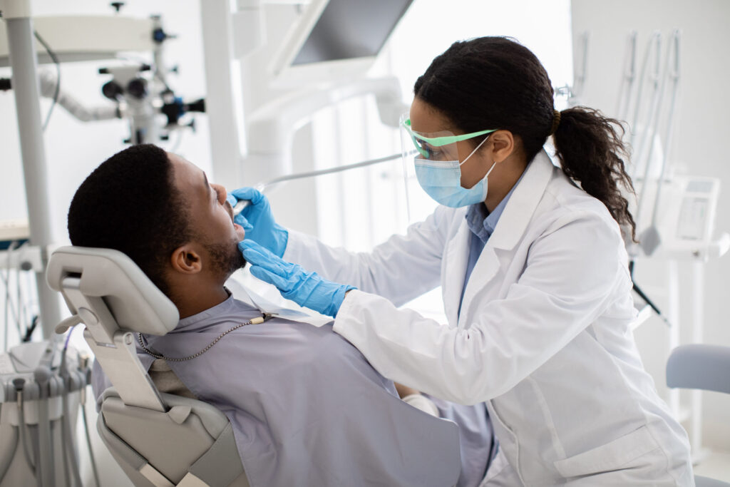 Portrait Of Black Male Patient Getting Teeth Treatment With Dentist At Clinic Portrait Of Black Male Patient Getting Teeth Treatment With Dentist At Clinic