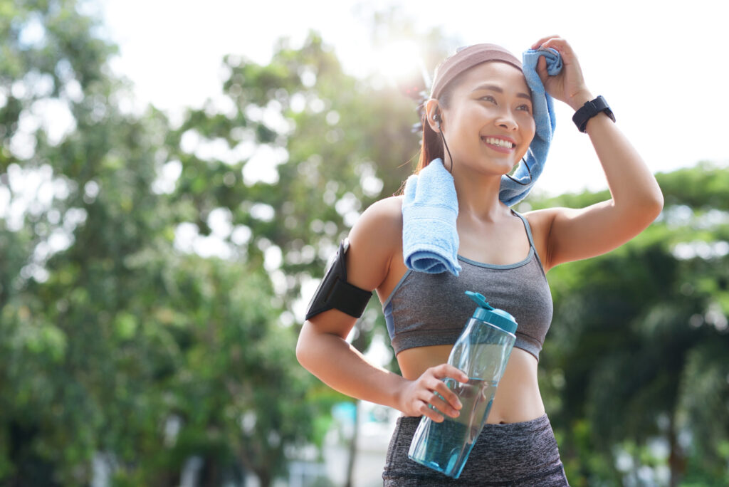 Cheerful sportswoman with bottle and towel Cheerful sportswoman with bottle and towel