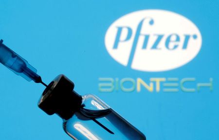Frasco e seringa em frente aos logos da Pfizer e da BioNTech em foto de ilustração Frasco e seringa em frente aos logos da Pfizer e da BioNTech em foto de ilustração