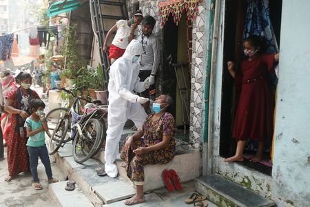 Profissional de saúde com máscara e trajes de proteção colhe amostra em paciente para exame de detecção de coronavírua em Mumbai Profissional de saúde com máscara e trajes de proteção colhe amostra em paciente para exame de detecção de coronavírua em Mumbai
