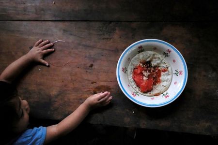 Criança de 1 ano e 10 meses tenta alcançar prato de comida em Palmilla, na Guatemala Criança de 1 ano e 10 meses tenta alcançar prato de comida em Palmilla, na Guatemala