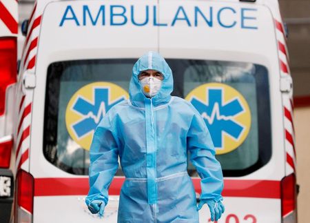 Profissional de saúde com trajes de proteção em frente a ambulância do lado de fora de hospital em Kiev, na Ucrânia