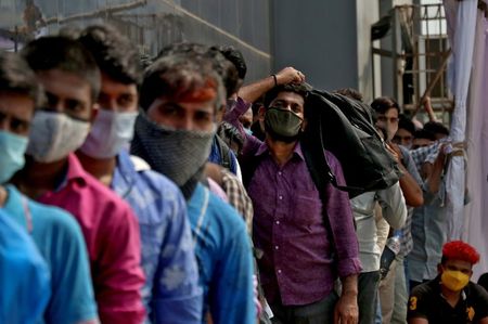 Pessos fazem fila para entrar em estação ferroviária em Mumbai, na Índia, em meio à pandemia de Covid-19