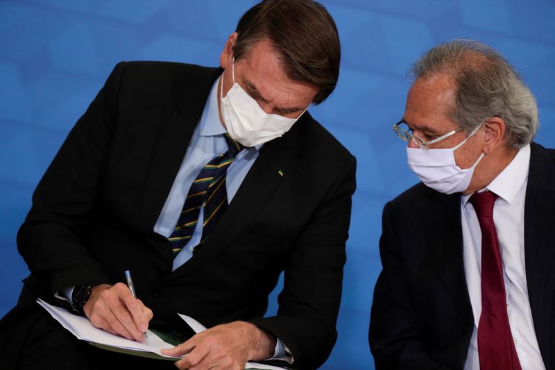 O presidente Jair Bolsonaro fala com o ministro da Economia, Paulo Guedes. 25/03/2021. REUTERS/Ueslei Marcelino.