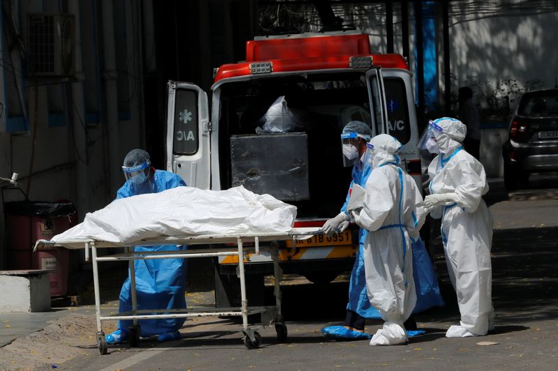 Profissionais de um necrotério colocam corpo de pessoa que morreu de Covid-19 em ambulância em Nova Délhi para transportá-lo para cremação