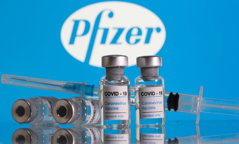 Frascos rotulados como de vacina contra Covid-19 em frente ao logo da Pfizer em foto de ilustração