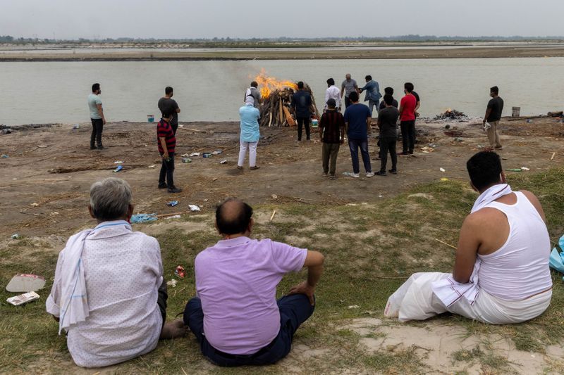 Familiares observam cremação de homem que morreu de Covid-19 às margens do rio Ganges no Estado indiano de Uttar Pradesh