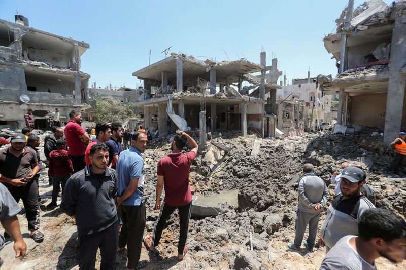 Palestinos se reúnem perto de casas destruídas por ataques aéreos e de artilharia de Israel no norte da Faixa de Gaza