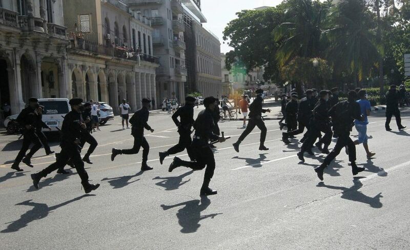 Policiais correm durante protestos em Cuba