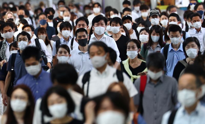 Passageiros usando máscaras de proteção caminham em direção à estação de Shinagawa, em Tóquio