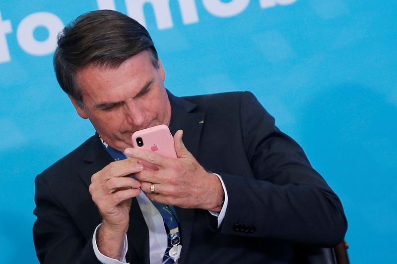 Presidente Jair Bolsonaro mexe em telefone celular durante cerimônia no Palácio do Planalto