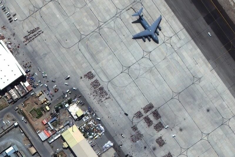 Grupos de pessoas aguarda na pista do aeroporto de Cabul