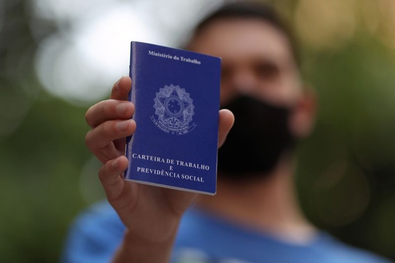 Homem mostra carteira de trabalho enquanto procura por vagas de emprego no centro de São Paulo