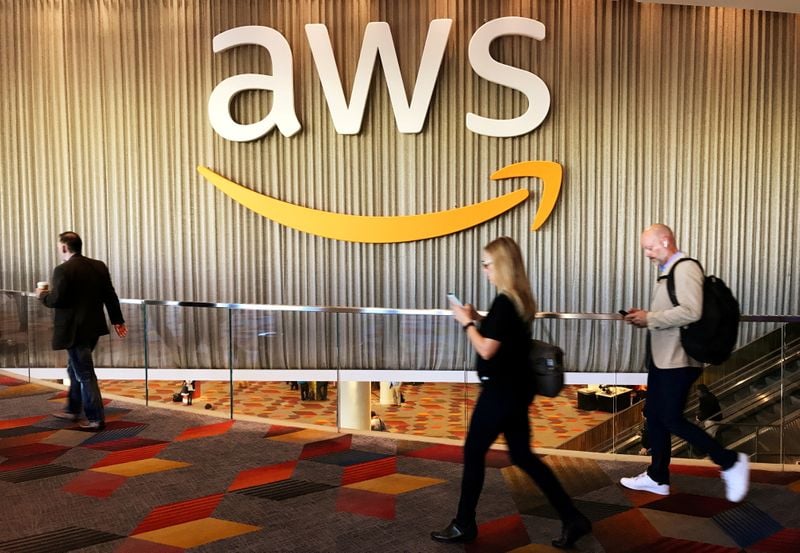 Participantes de evento da Amazon Web Services passam em frente a logotipo da companhia