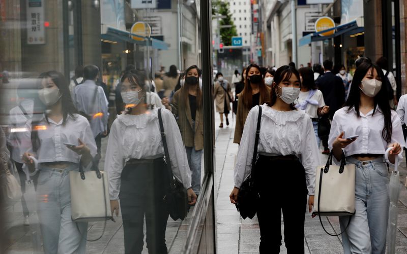 Pessoas usando máscaras de proteção caminham em distrito comercial em Tóquio