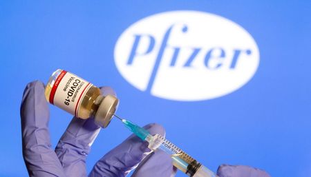 Frasco rotulado como de vacina contra Covid-19 em frente ao logo da Pfizer em foto de ilustração