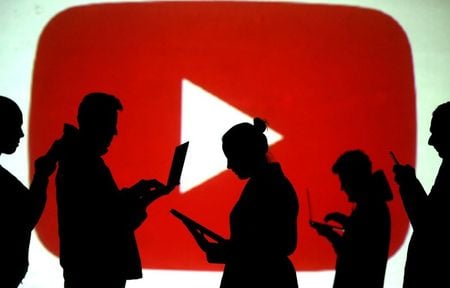 Silhuetas de usuários de dispositivos móveis com logotipo do Youtube ao fundo.