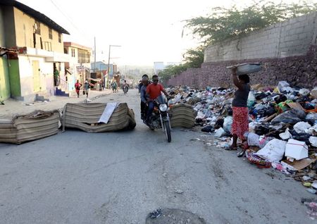 Pessoas passam por barricada em rua de Porto Príncipe, no Haiti