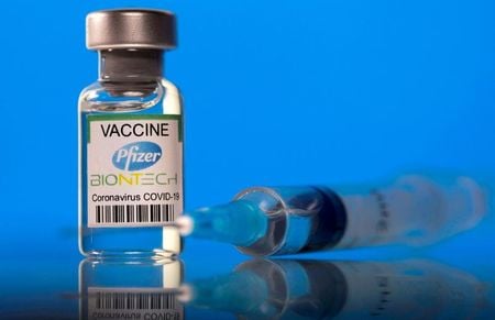Frasco rotulado como de vacina da Pfizer contra Covid-19 ao lado de seringa em foto de ilustração
