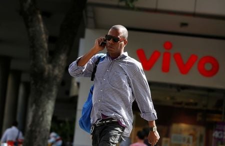 Homem fala ao celular enquanto caminha em frente a uma loja da Vivo, no centro do Rio de Janeiro