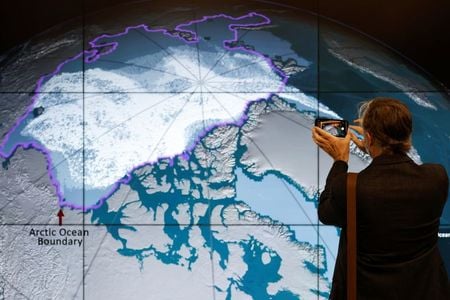 Delegado tira foto de mapa que mostra cobertura de gelo durante a COP26 em Glasgow, na Escócia