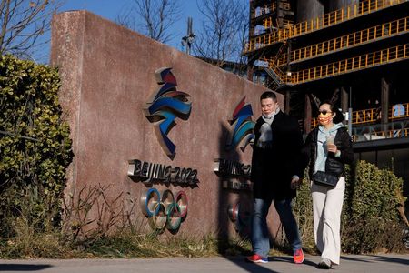 Duas pessoas caminham em frente à sede do comitê organizador dos Jogos Olímpicos e Paraolímpicos de Inverno de 2022 em Pequim, China