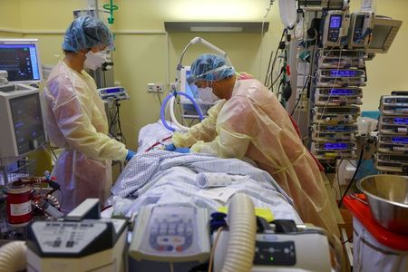 Equipes médicas com trajes de proteção tratam paciente com Covid-19 em unidade de terapia intensiva de hospital em Berlim