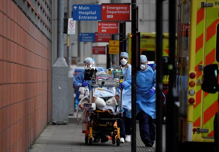 Profissionais de saúde transportam paciente entre ambulâncias durante pandemia de Covid-19 em hospital de Londres