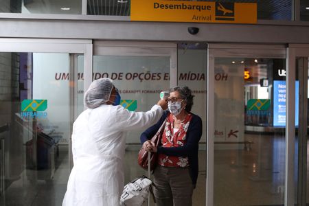 Funcionária mede temperatura de passageiro no aeroporto de Congonhas, em São Paulo